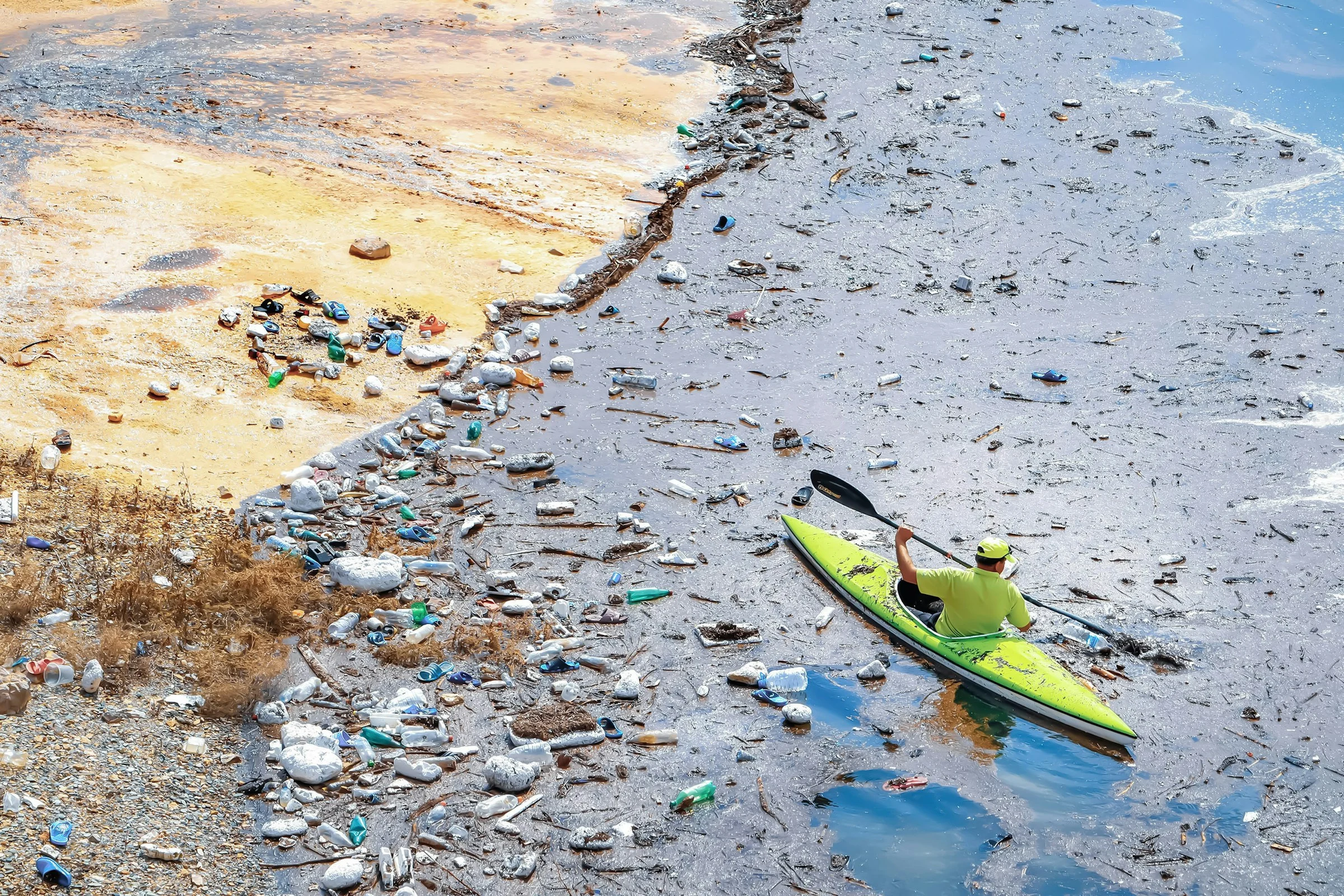 a man in kayak amongst ocean waste